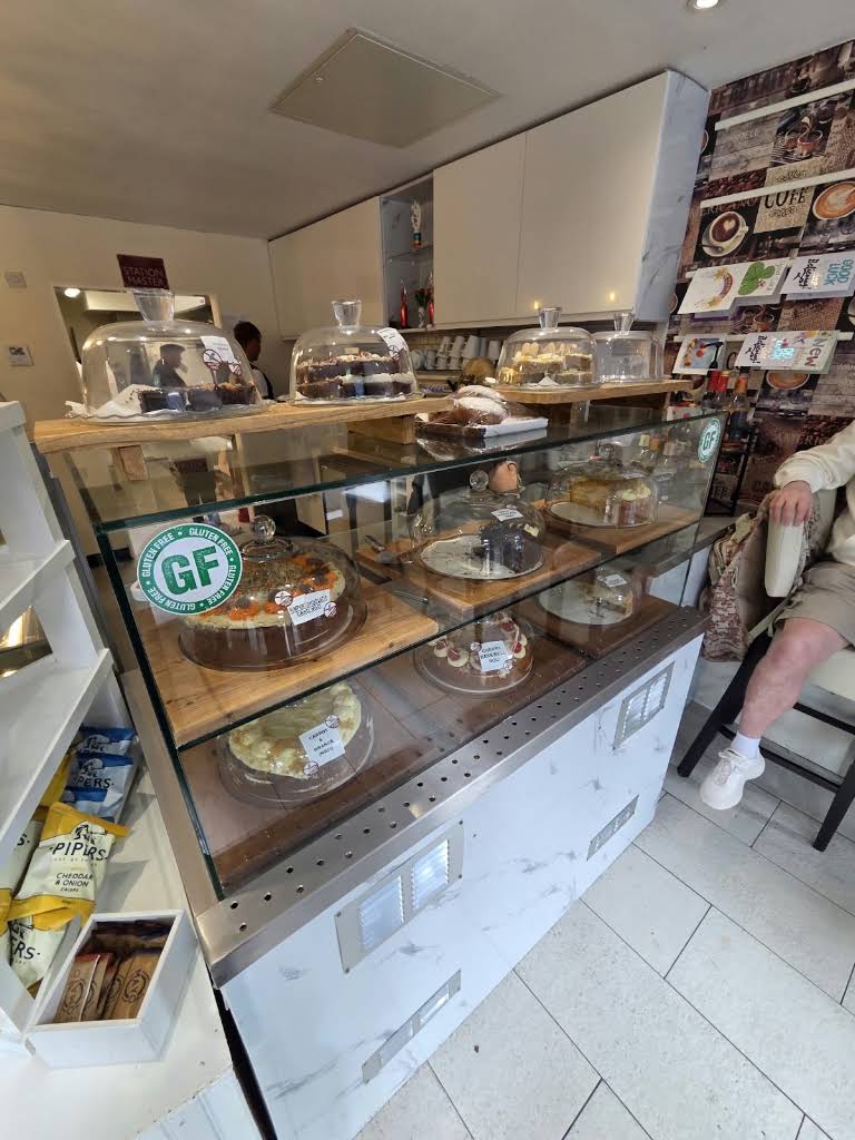Café 24’s glass cake counter with cakes displayed on wooden shelves and under glass domes.